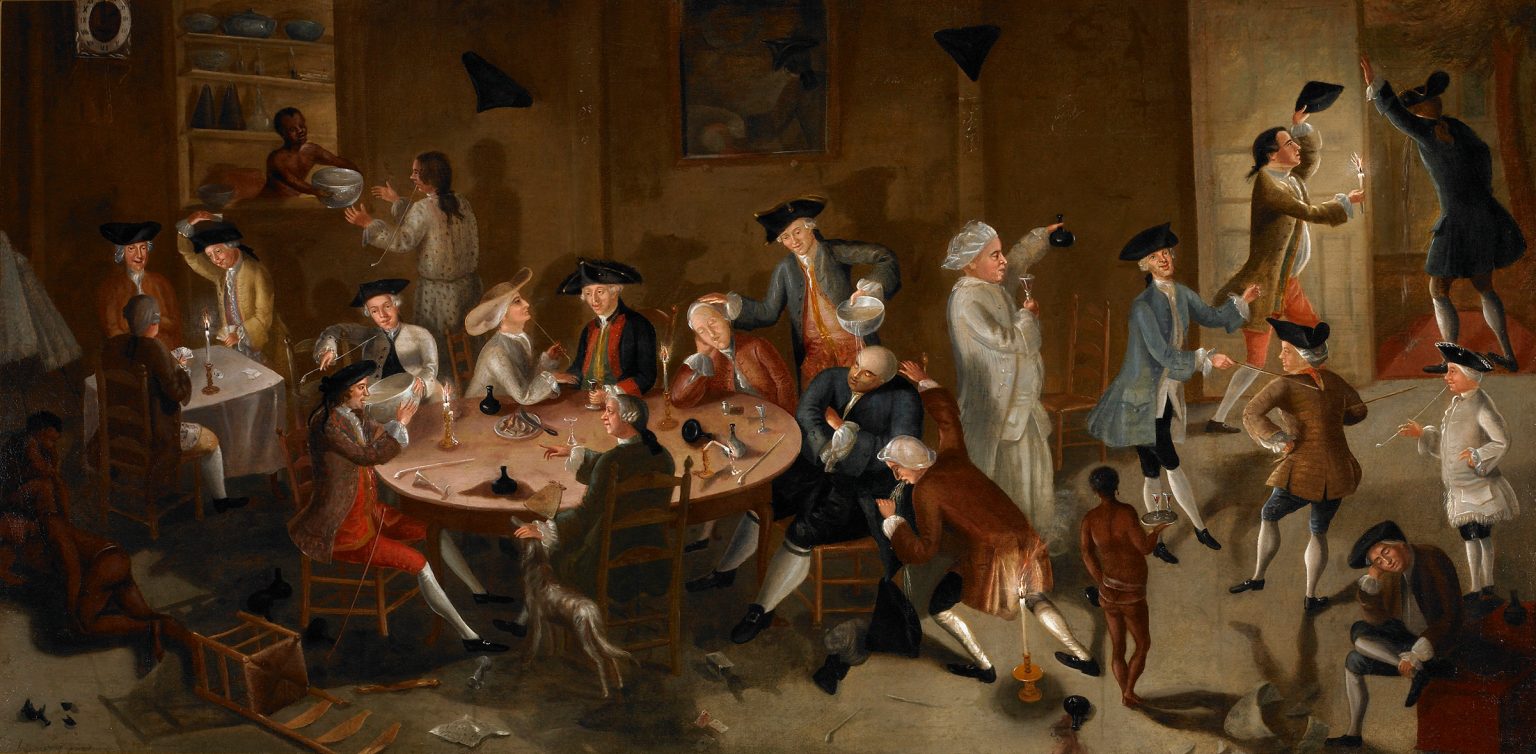 Colorful painting of ornately dressed men indulging in food and drink provided by naked black servants.
